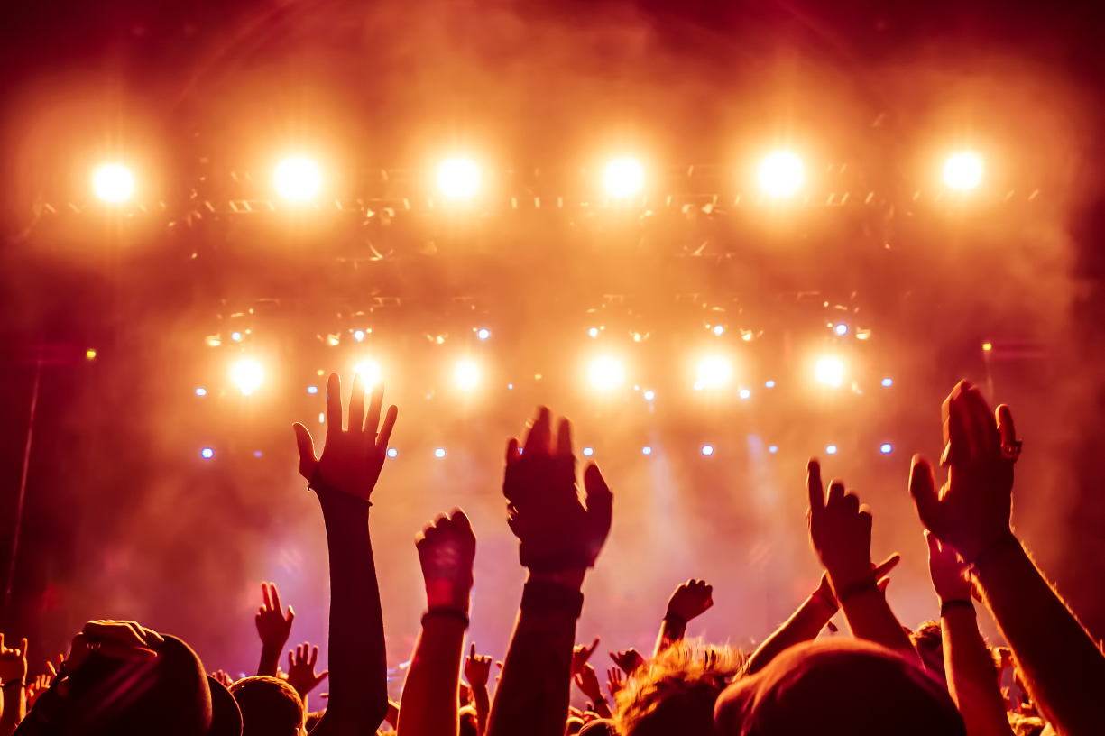 crowded venue with stage lighting and hands in the air