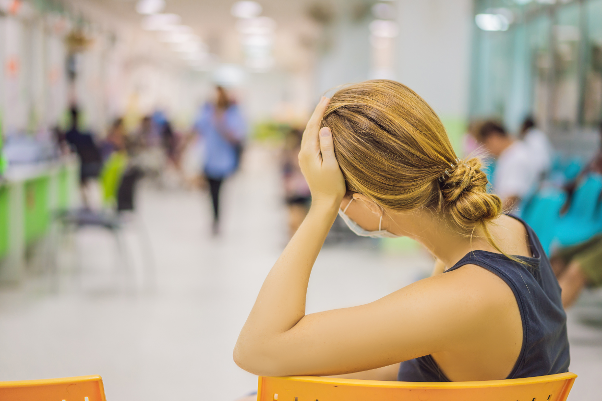 woman with her hand holding hear head up in a hospital waiting room